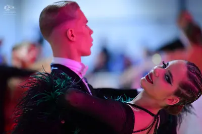Dancesport competitor: Male dancer: black suit with white shirt and black feather-like detailing on the