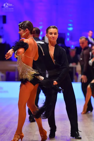 Dancesport competitor: Female dancer: silver sequined Latin dance top with a black skirt adorned with l