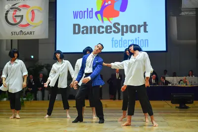 Dancesport competitor: Three dancers are wearing matching costumes consisting of white long-sleeved but