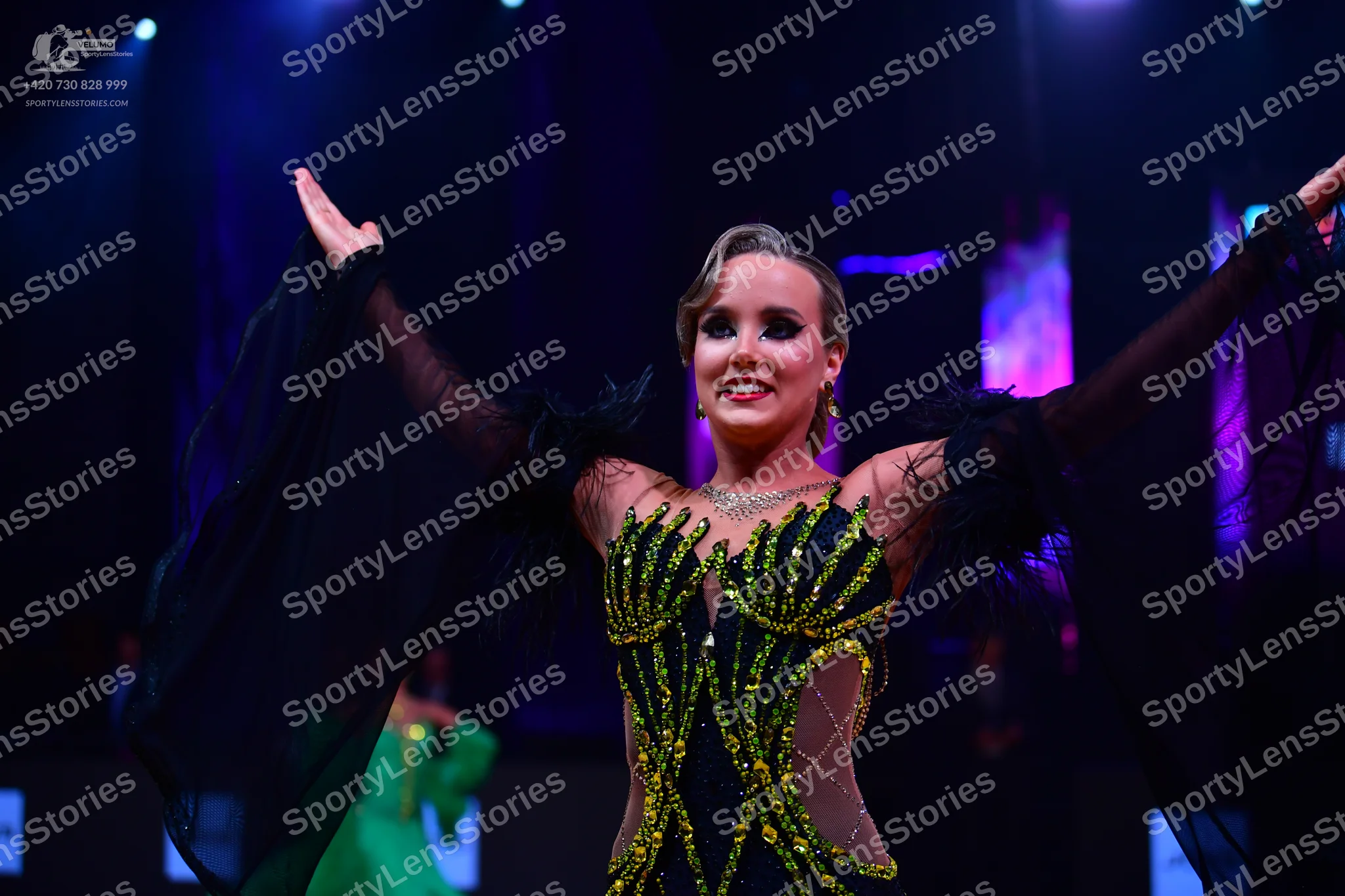 Dancesport competitor: Female dancer in foreground: black latin dress with gold sequin patterns, nude m
