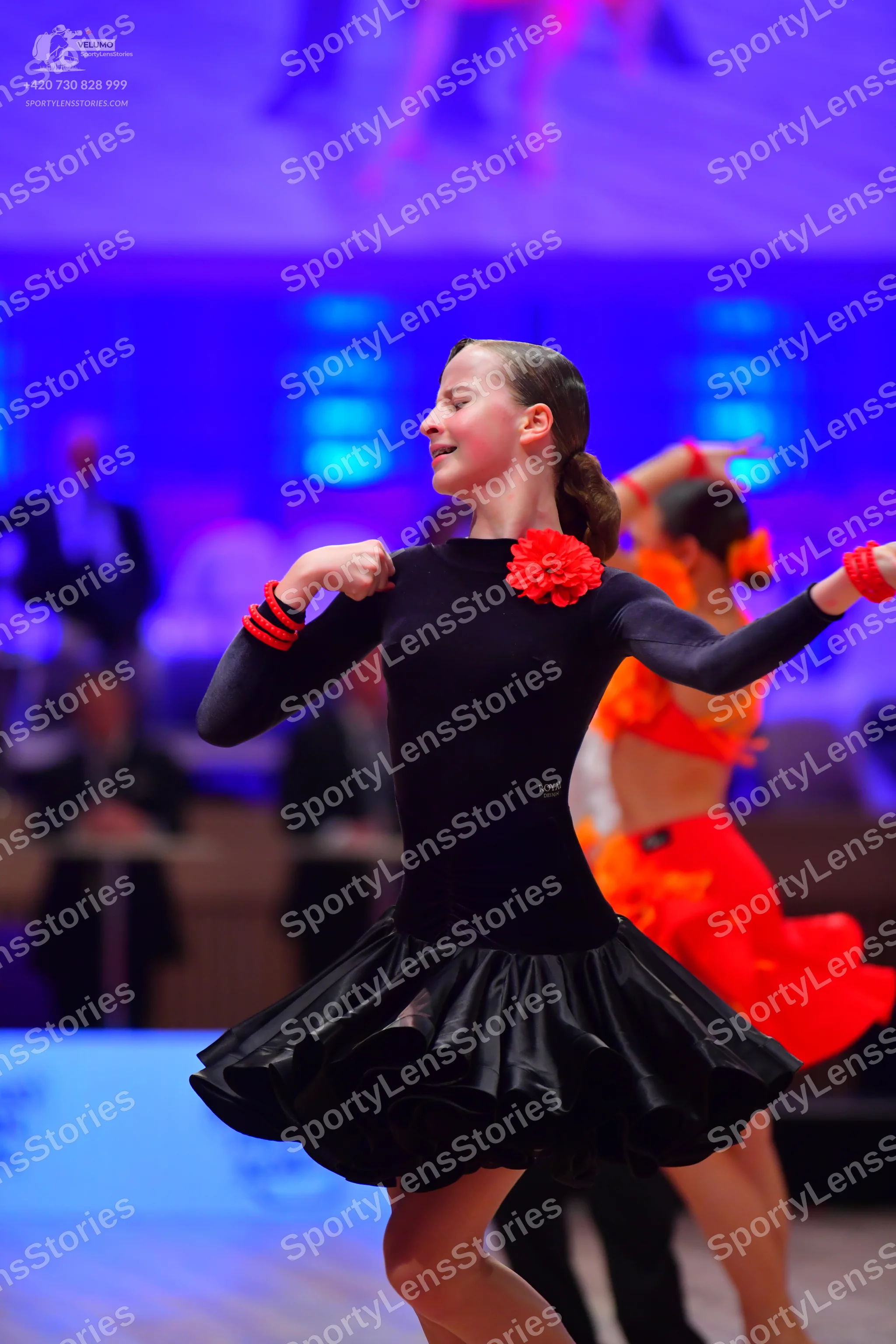 Dancesport competitor: Female dancer in foreground: black long-sleeve dance dress with a voluminous ruf