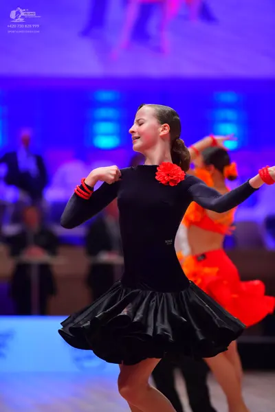Dancesport competitor: Female dancer in foreground: black long-sleeve dance dress with a voluminous ruf
