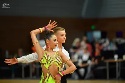 Dancesport competitor: Female dancer: neon yellow and purple Latin dance costume with cutouts and thin 