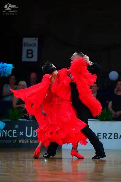 Dancesport competitor: Female dancer: red voluminous ballroom dress with many layers of ruffled, flowin