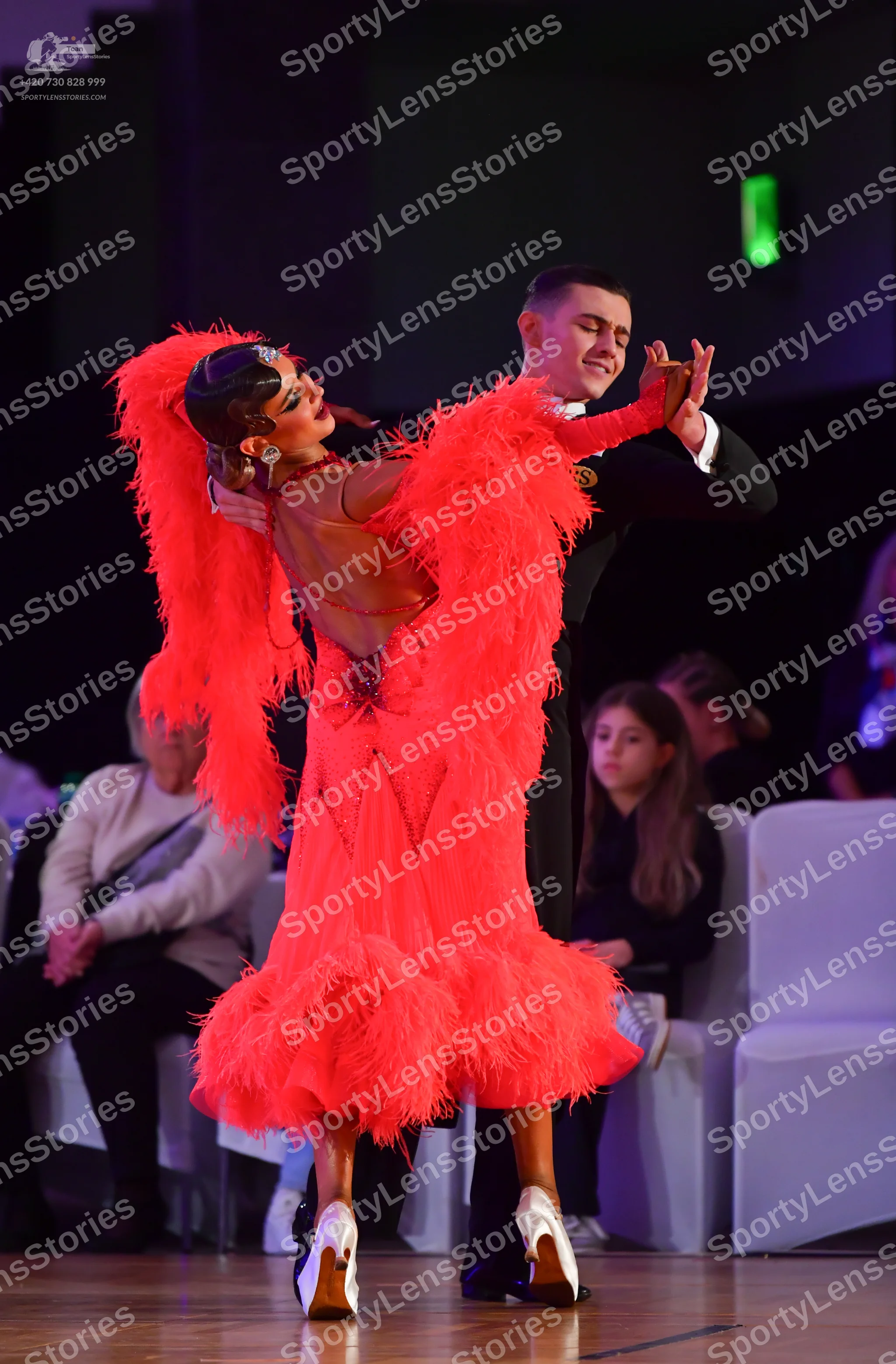 Dancesport competitor: Female dancer: red Latin dress with long, voluminous feather fringe and white da