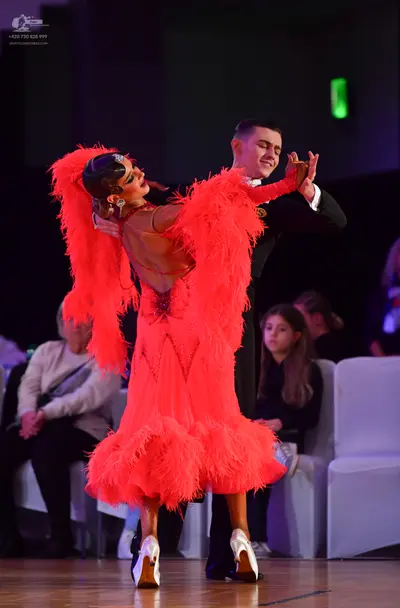 Dancesport competitor: Female dancer: red Latin dress with long, voluminous feather fringe and white da