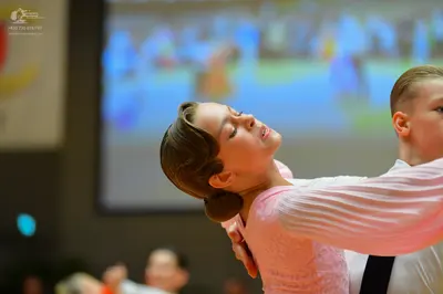 Dancesport competitor: Female dancer: light pink long-sleeved dress with a textured or lace bodice and 