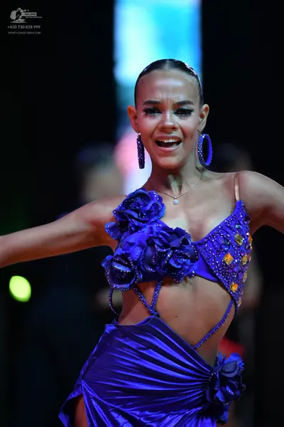 Dancesport competitor: Female dancer: purple latin dress with large fabric flowers, sequins, and thin b