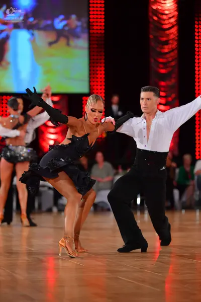 Dancesport competitor: Female dancer: black Latin dress with textured ruffle details, long black gloves