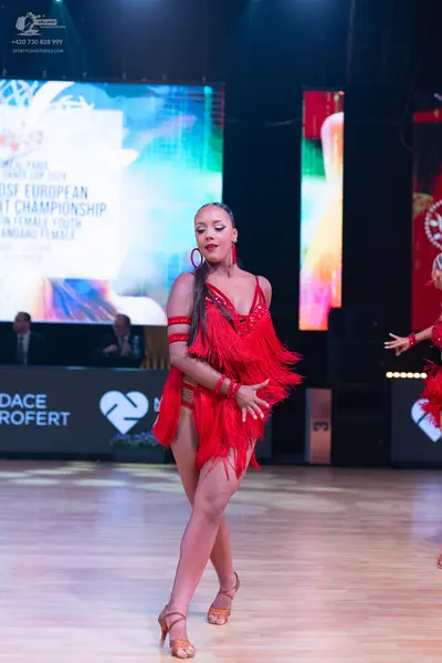 Dancesport competitor: Female dancer: red latin dress with long fringe, red armbands, and red bracelets