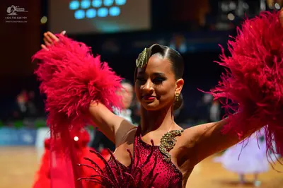 Dancesport competitor: Female dancer: red Latin dance dress with sequins and large red feathery arm pie