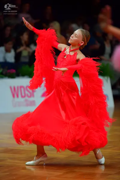Dancesport competitor: Female dancer: red latin dress with voluminous red feather-like fringe on the sl