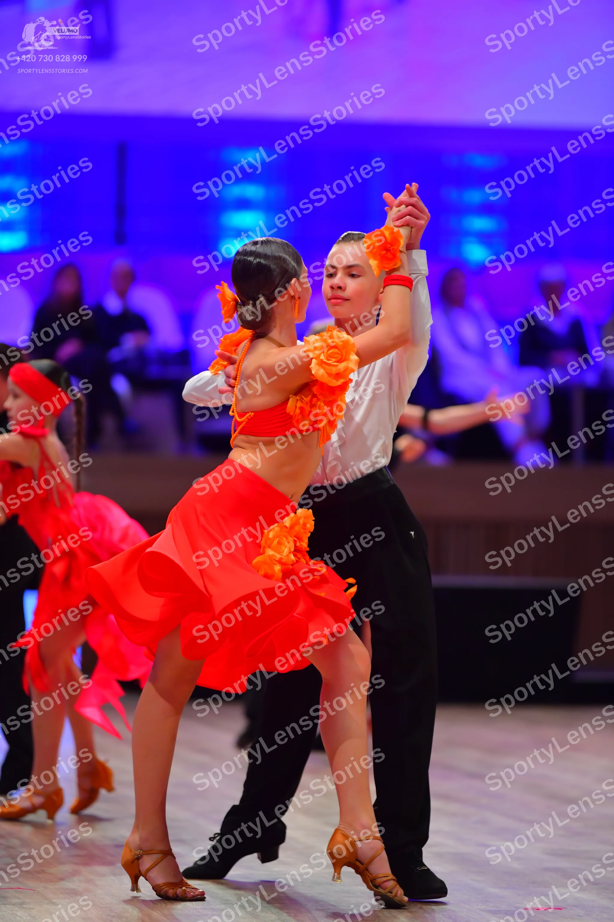 Dancesport competitor: Female dancer: red and orange two-piece Latin costume featuring a crop top and s