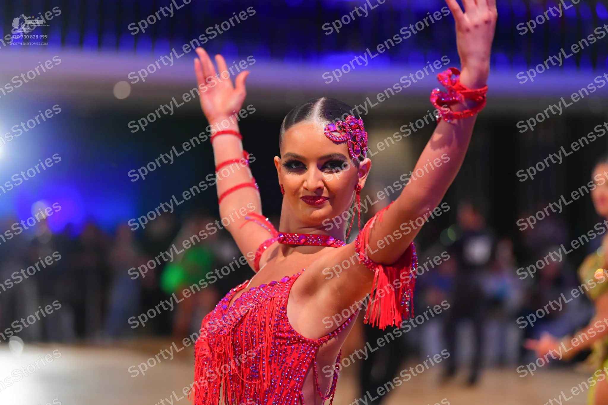 Dancesport competitor: Female dancer in foreground: pink sequined Latin dress with fringe, matching pin