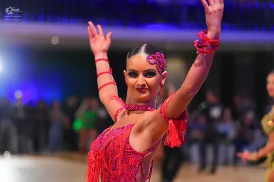 Dancesport competitor: Female dancer in foreground: pink sequined Latin dress with fringe, matching pin