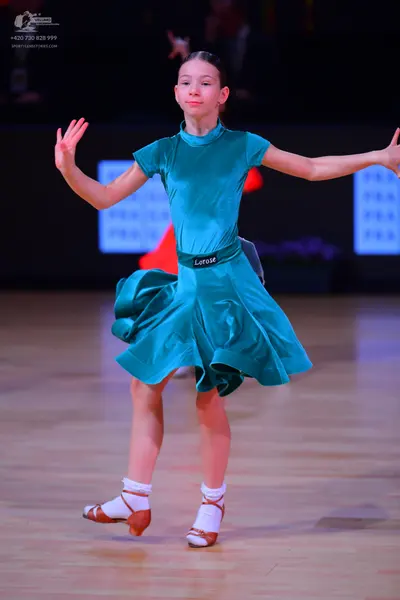 Dancesport competitor: Female dancer: teal satin-like dress with short sleeves, a high neck, and a flar