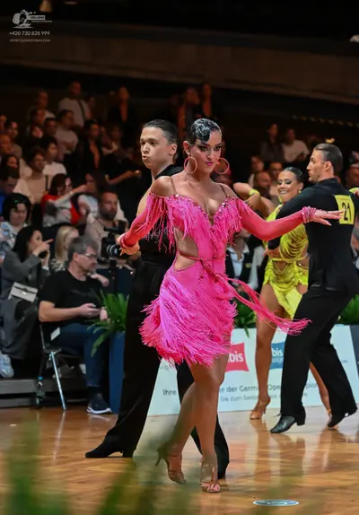 Dancesport competitor #21: Female dancer in foreground: pink latin dress with long sleeves, cutouts, and fr