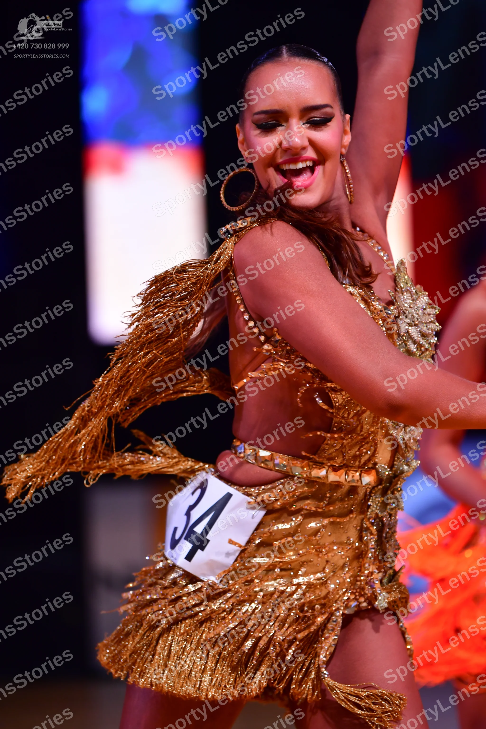 Dancesport competitor: Female dancer: gold sequined Latin dress with fringe and large gold hoop earring