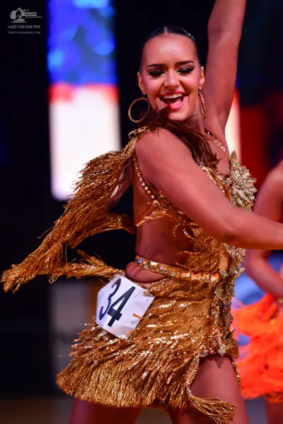 Dancesport competitor: Female dancer: gold sequined Latin dress with fringe and large gold hoop earring