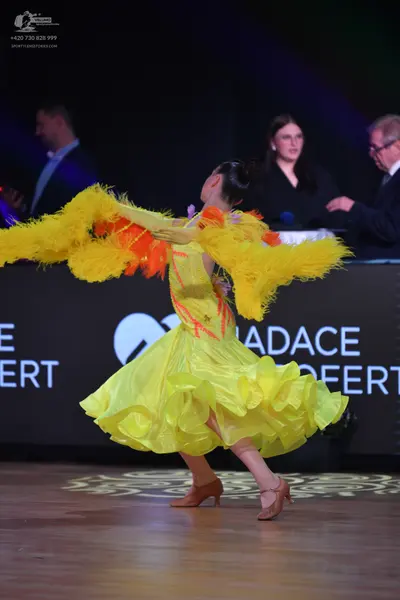 Dancesport competitor: Female dancer: bright yellow Latin dance dress with a voluminous, ruffled skirt 