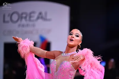 Dancesport competitor: Female dancer: pink latin dress with sequins, nude mesh neckline, and large pink
