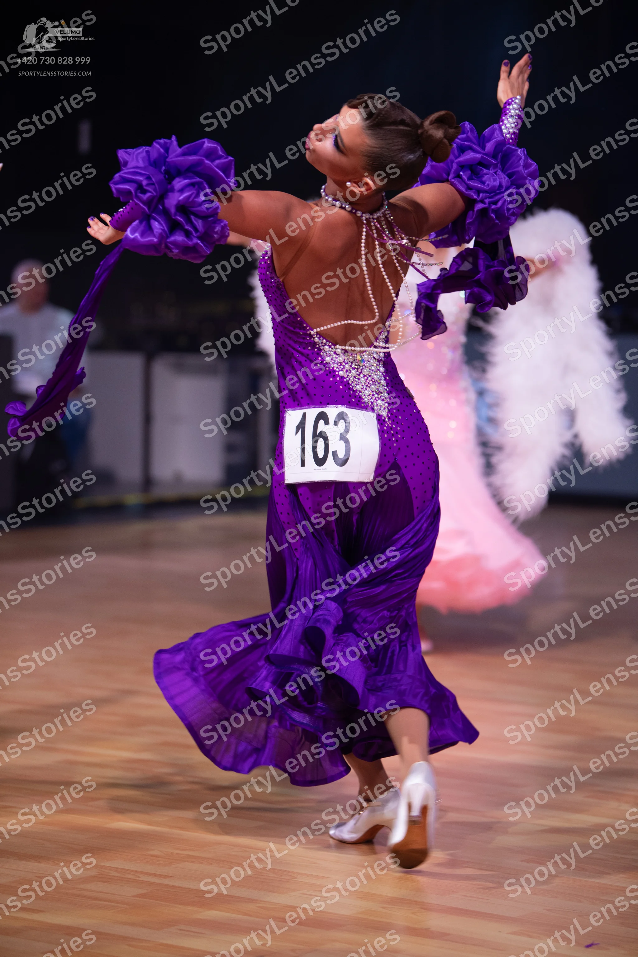 Dancesport competitor: Female dancer 1: purple ballroom dress with satin-like fabric, large ruffled sle