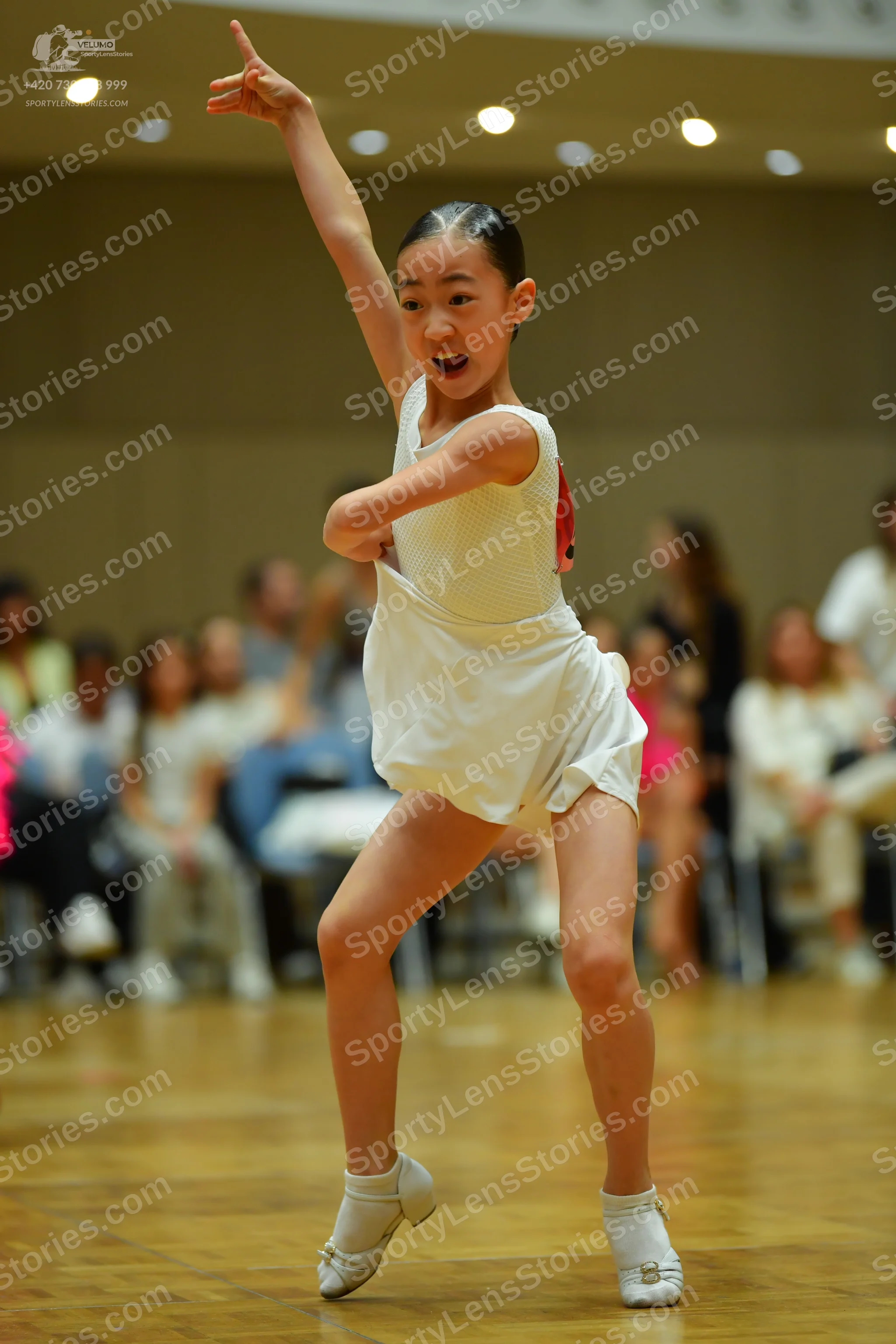 Dancesport competitor: Female dancer: white sleeveless dance costume with a textured/mesh top and a sho