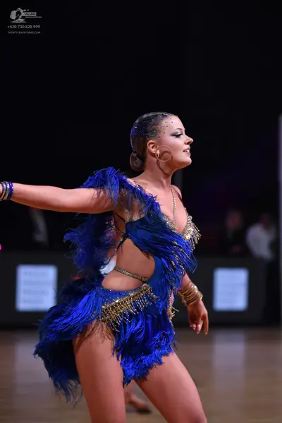 Dancesport competitor: Female dancer: royal blue Latin dance costume with blue fringe, gold sequin embe