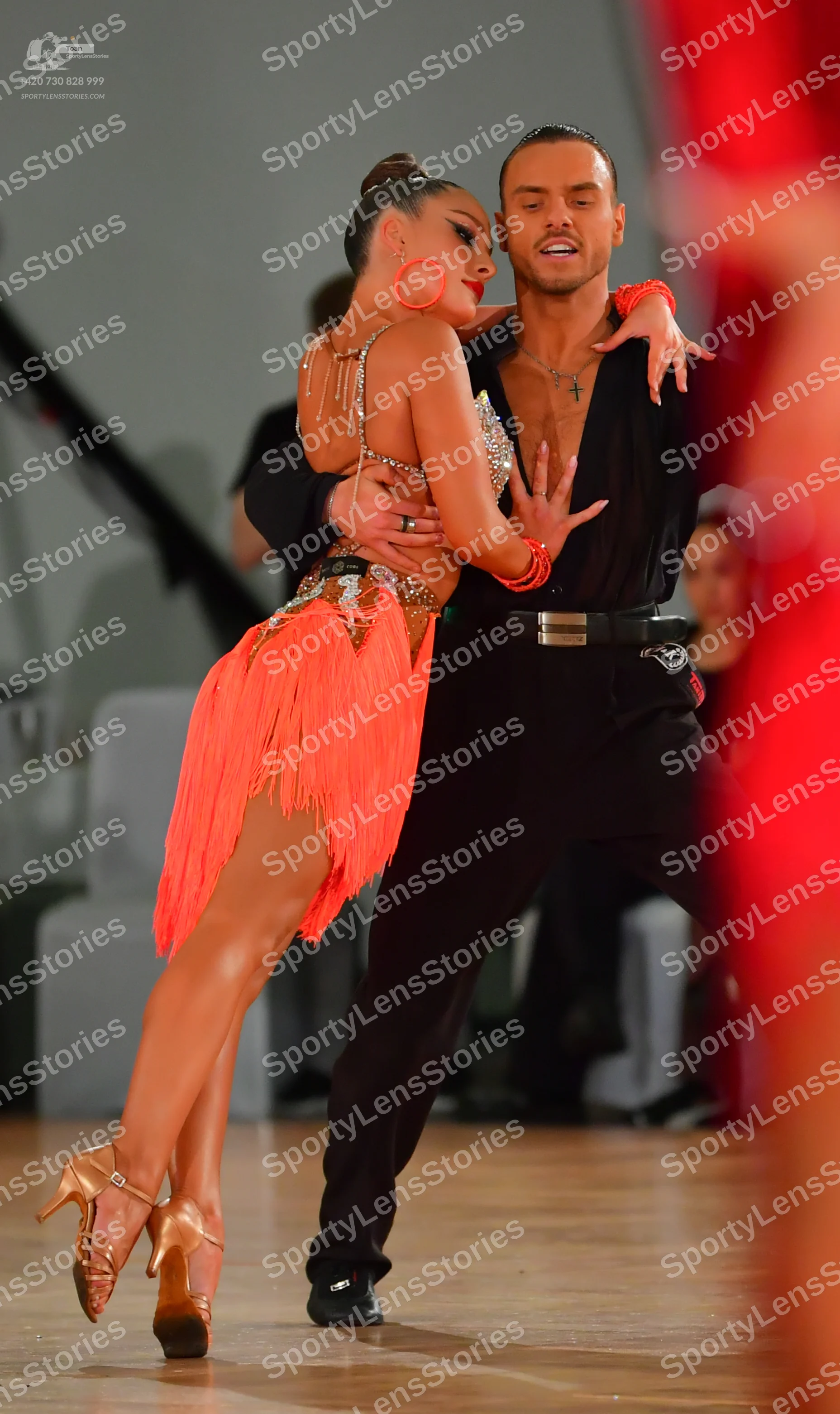Dancesport competitor: Male dancer: black shirt with a deep V-neck, black trousers, black belt with a s