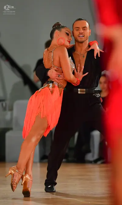 Dancesport competitor: Male dancer: black shirt with a deep V-neck, black trousers, black belt with a s