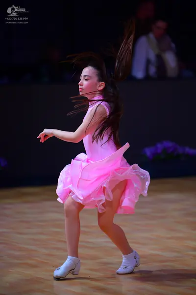 Dancesport competitor: Female dancer: pink sleeveless Latin dress with a voluminous ruffled skirt
