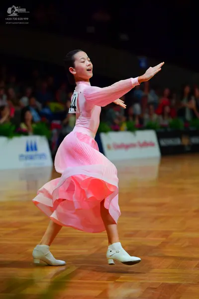 Dancesport competitor: Female dancer: pink long-sleeved ballroom dress with a voluminous, ruffled skirt