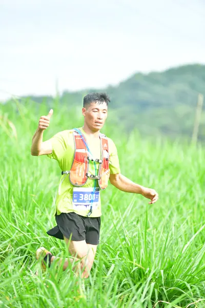 Marathon runner #3808: Runner 1: lime green shirt, black shorts, black and white shoes, hydration vest