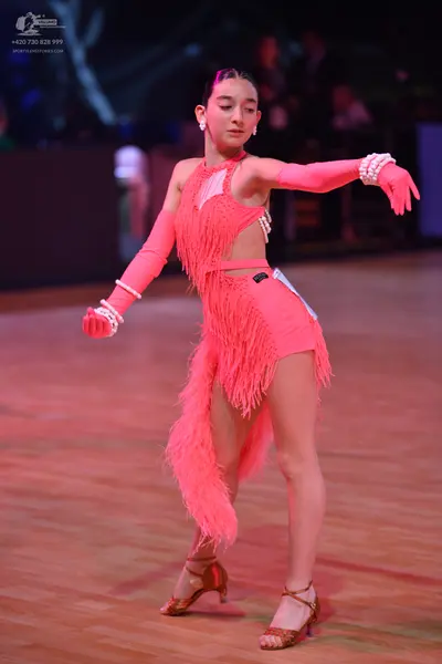 Dancesport competitor: Female dancer: pink Latin dance dress with long fringe, white/silver sequin trim