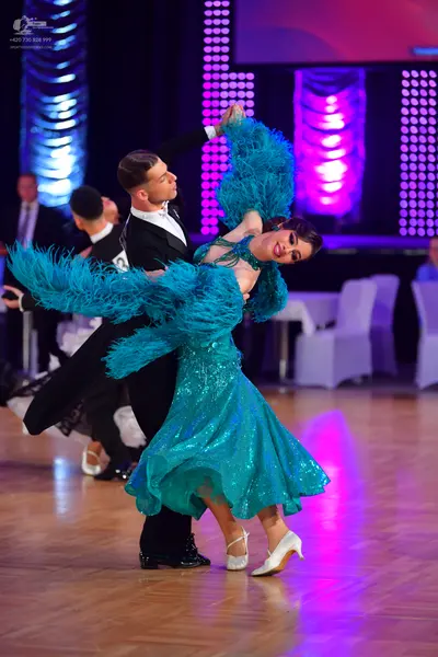 Dancesport competitor: Female dancer: teal sequined latin dress with large, voluminous, teal feather-li