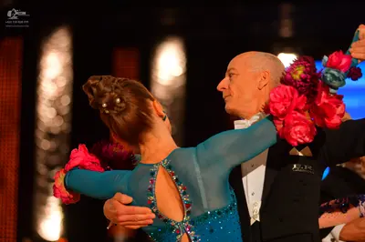 Dancesport competitor: Female dancer: teal long-sleeved Latin dress with a cutout on the back, embellis