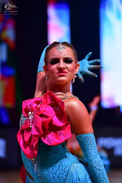 Dancesport competitor: Female dancer: light blue sequined latin dress with a large pink sequined flower