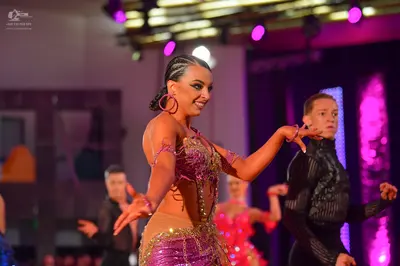 Dancesport competitor: Female dancer in foreground: nude-colored Latin costume with heavy gold and pink
