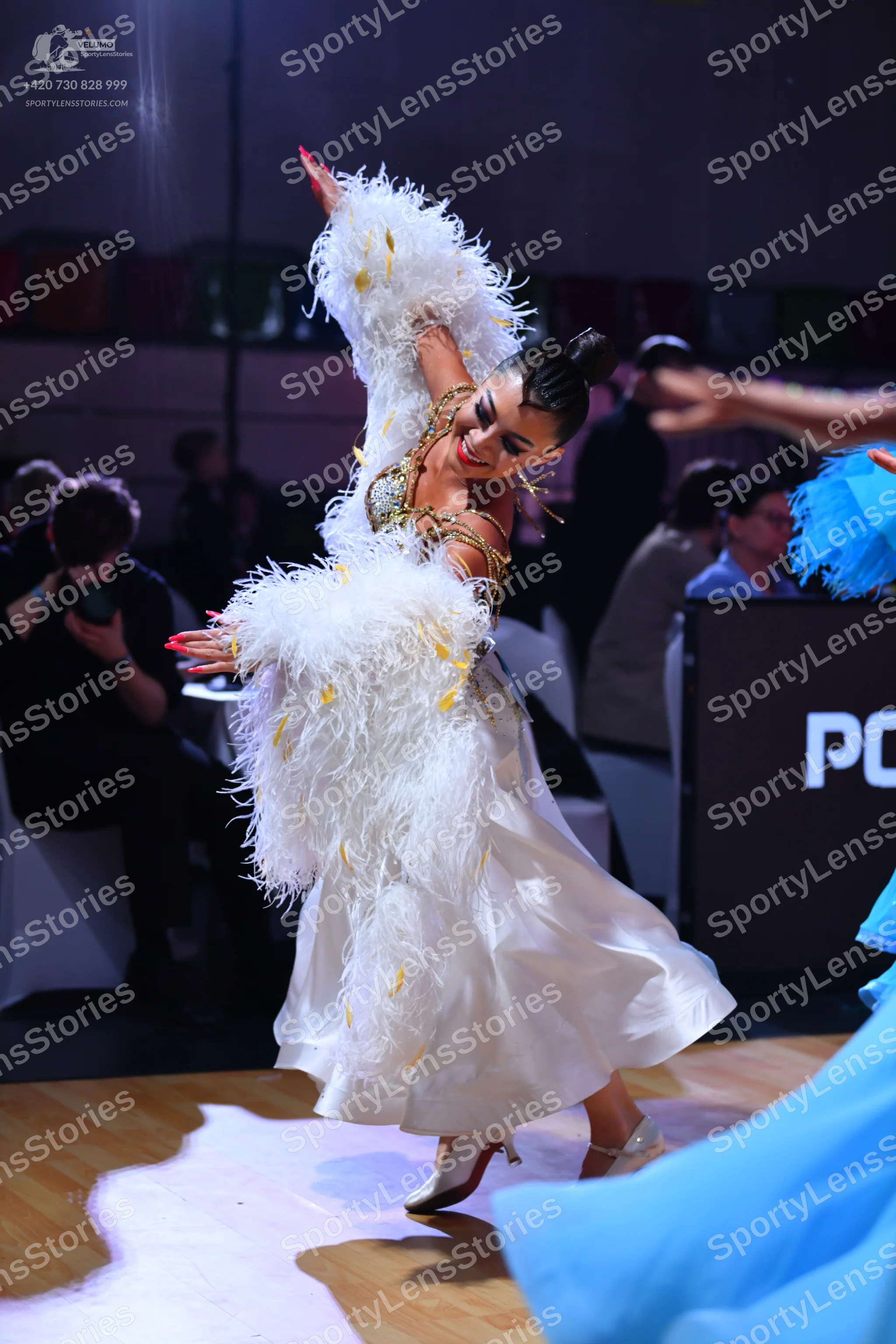 Dancesport competitor: Female dancer: white ballgown with voluminous white feather trim on the sleeves