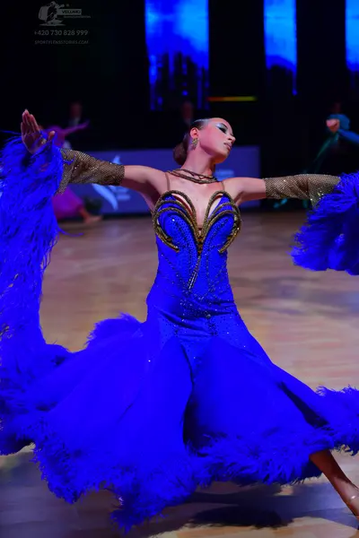 Dancesport competitor: Female dancer: bright blue Latin dance dress featuring blue feather trim on the 