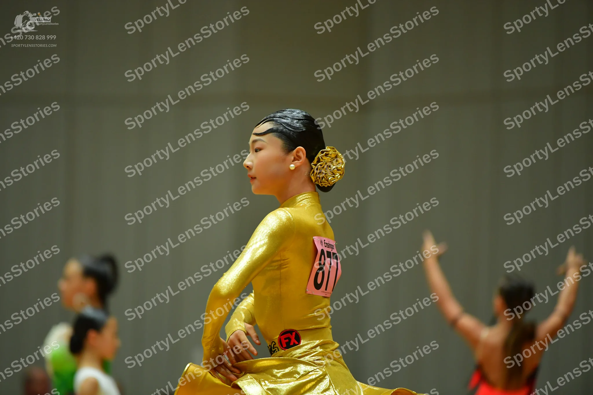 Dancesport competitor #877: Female dancer (center): gold metallic long-sleeved dress with a high neck and a