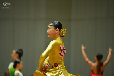 Dancesport competitor #877: Female dancer (center): gold metallic long-sleeved dress with a high neck and a 