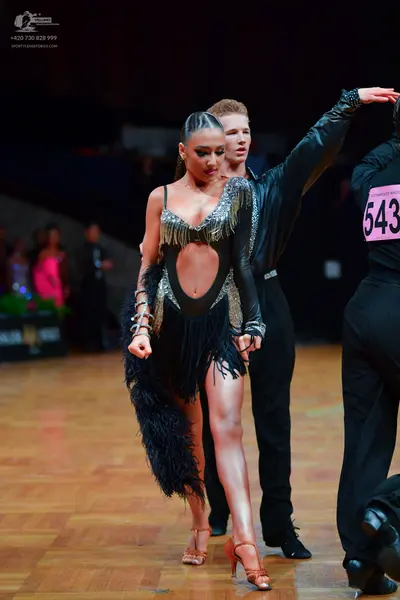 Dancesport competitor: Female dancer: black Latin dress with silver sequin fringe, cutouts, and a long 