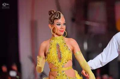 Dancesport competitor: Female dancer: yellow Latin dance dress with sequins, cutouts, and a high neck, 