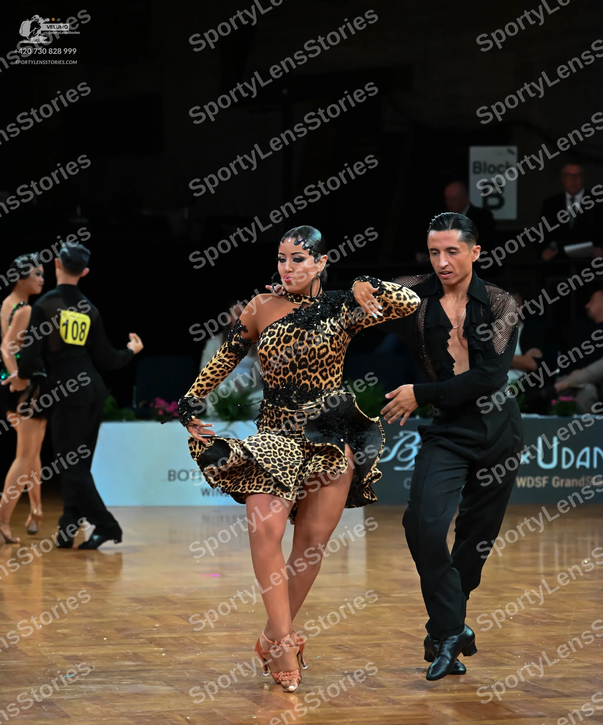 Dancesport competitor: Female dancer in center: leopard print Latin dress with long sleeves and black l