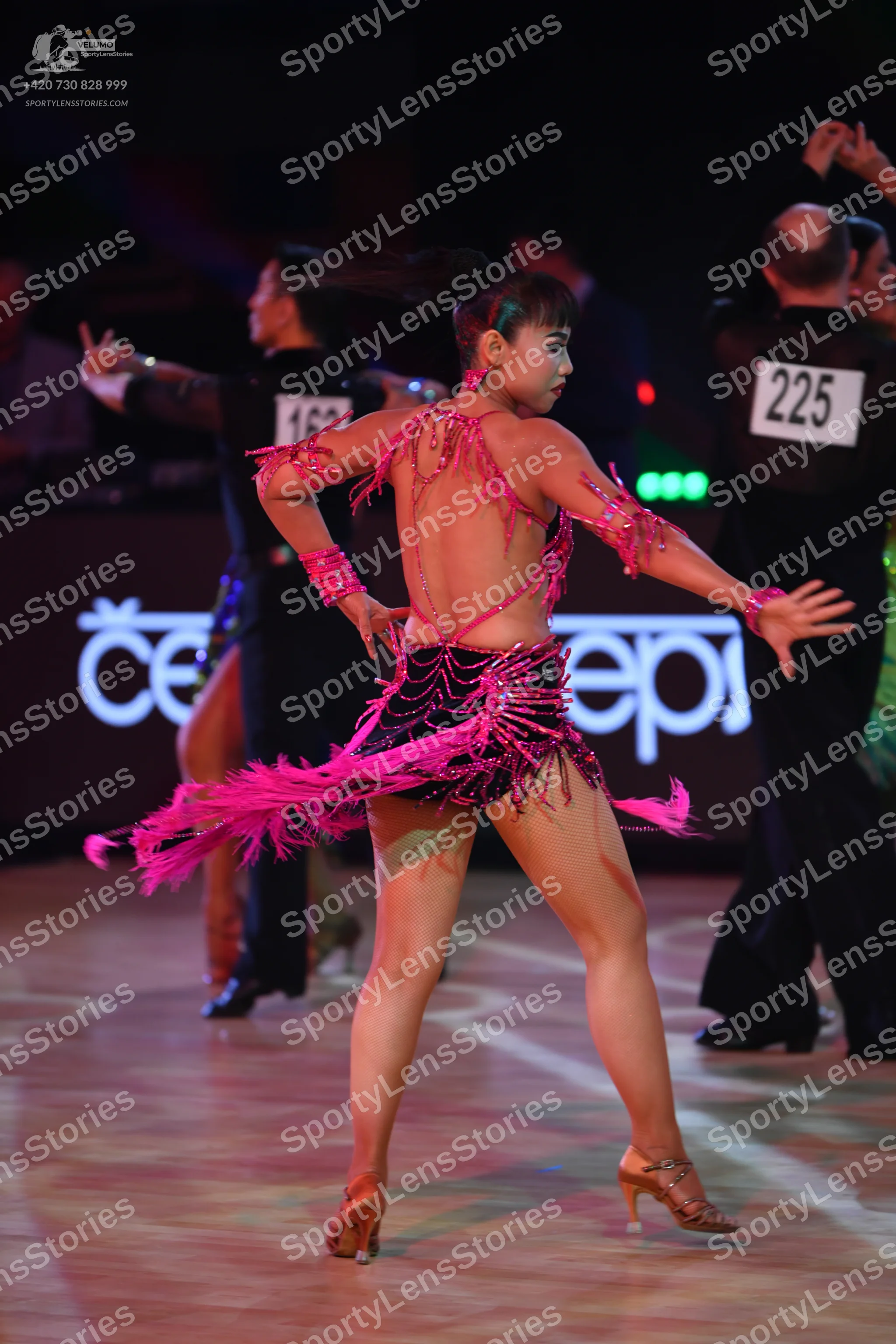 Dancesport competitor: Female dancer: pink Latin dress with black sequins and long pink fringe
