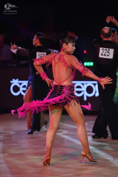 Dancesport competitor: Female dancer: pink Latin dress with black sequins and long pink fringe