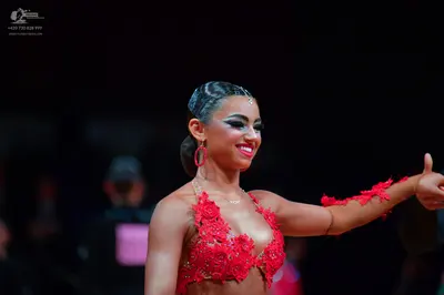 Dancesport competitor: Female dancer: red Latin costume featuring intricate red lace appliqués on a bra