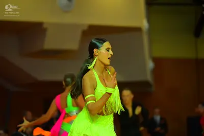 Dancesport competitor: Female dancer: bright neon yellow/green Latin dress with fringe and matching wri