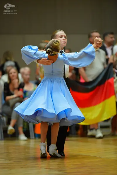 Dancesport competitor: Female dancer: light blue ballroom dress with long, voluminous puffed sleeves an